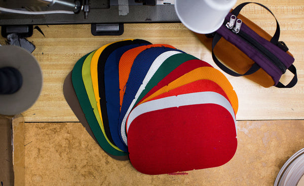 A Grab Bag and die-cut Grab Bag parts on a sewing machine table in the TOM BIHN factory.